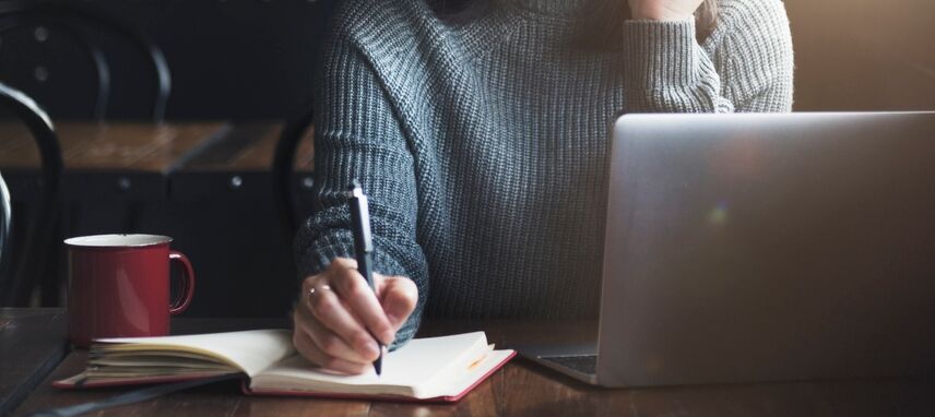 A person making notes from their laptop