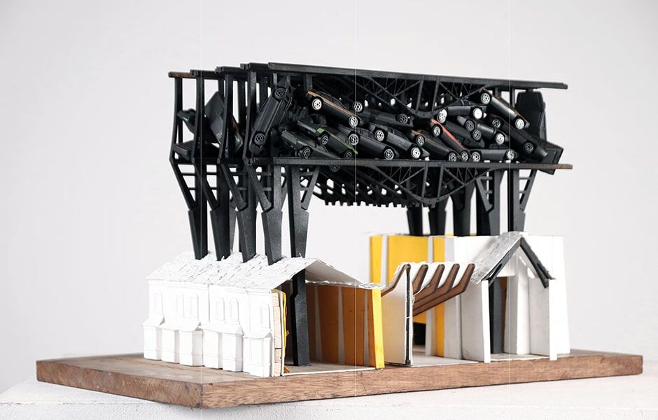 Model of buildings with black cars suspended above