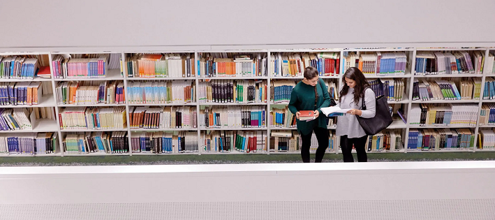 Two students looking at books near shelves in Curzon Library.