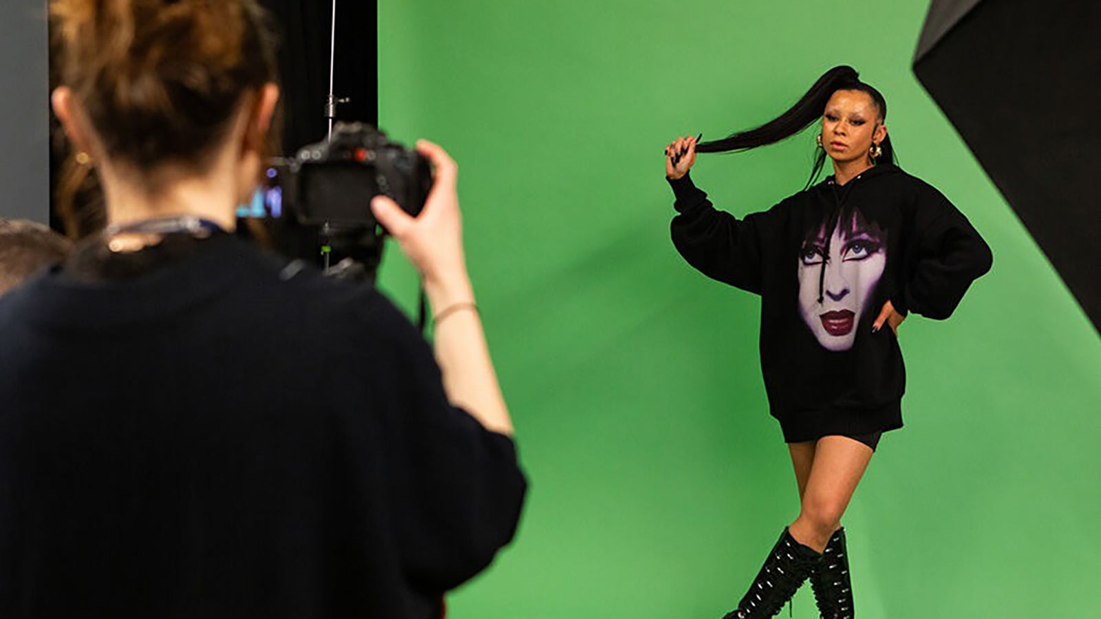 Student taking photos of another student in front of a green screen 