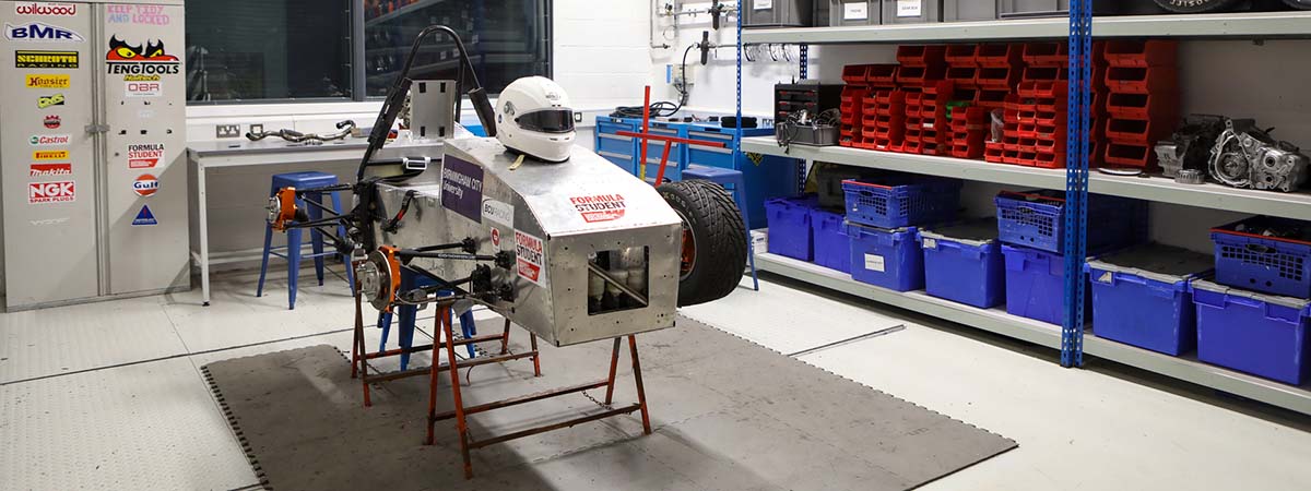 Two students working on a racing car in the Formula Student garage. 
