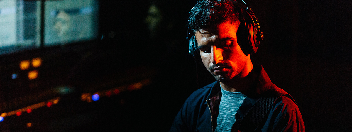 Student wearing headphones in sound studio with red light on face