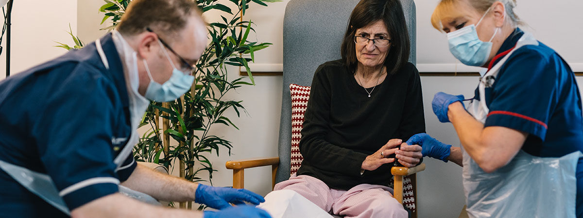 Two student nurses monitoring patient  sat in chair