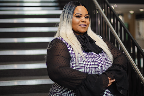 Proud black woman with long blonde hair standing on stairs