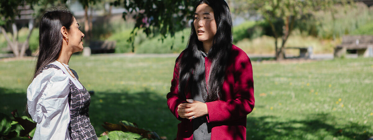 Two PhD students having a conversation in green outside space