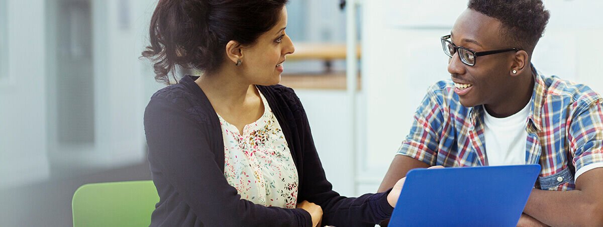 Staff and student member talking around a laptop
